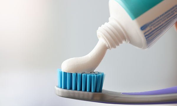 White toothpaste is applied to toothbrush. Oral Care Concept